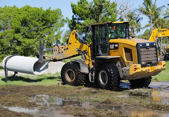 Front loader moving drainage pipes on site in Venice, FL.